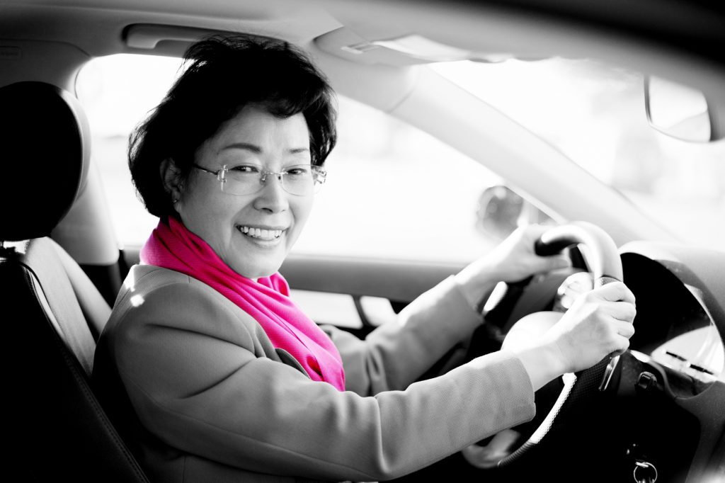 A woman wearing a pink scarf and driving a pink taxi, illustrating the opportunity for women to work for women's rights and gender equality with pink transportation (image © Hannah Arista).