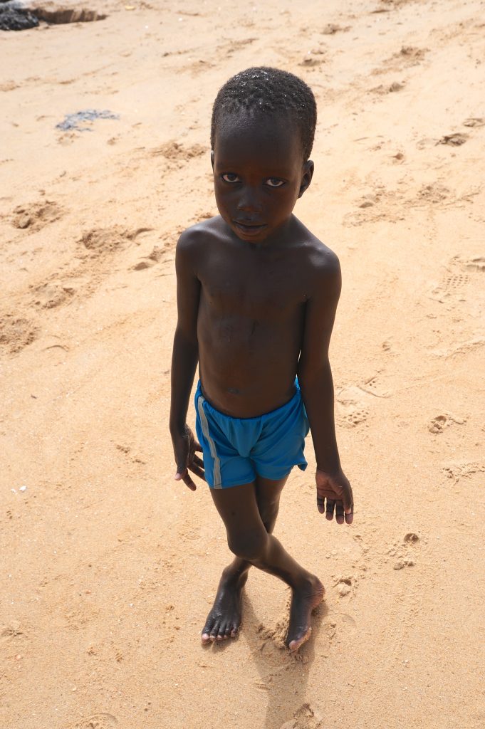 Small boy on the beach in M'Bour, Senegal, offering travel adventures and a photographer's dream of Senegal portraits. (Image © Meredith Mullins.)