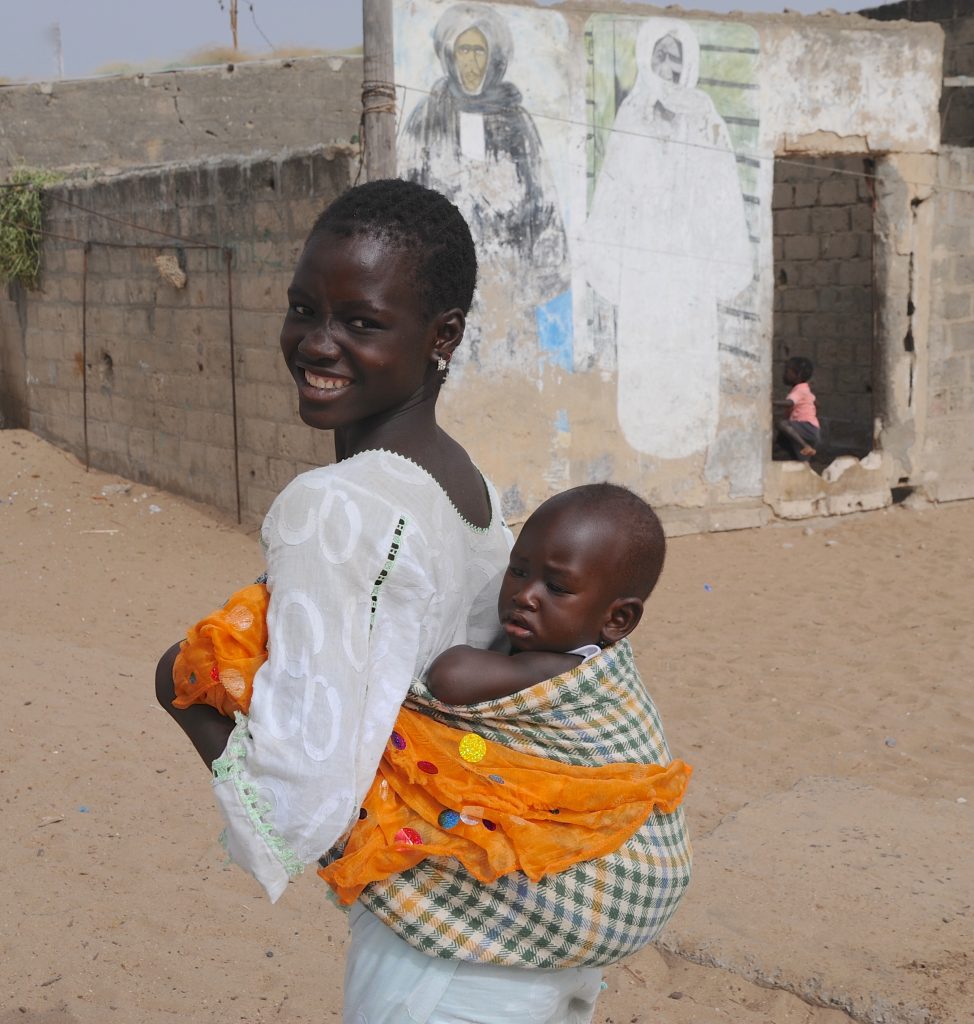 Woman with baby on her back in M'Bour, Senegal, offering travel adventures and a photographer's dream of images. (Image © Meredith Mullins.)