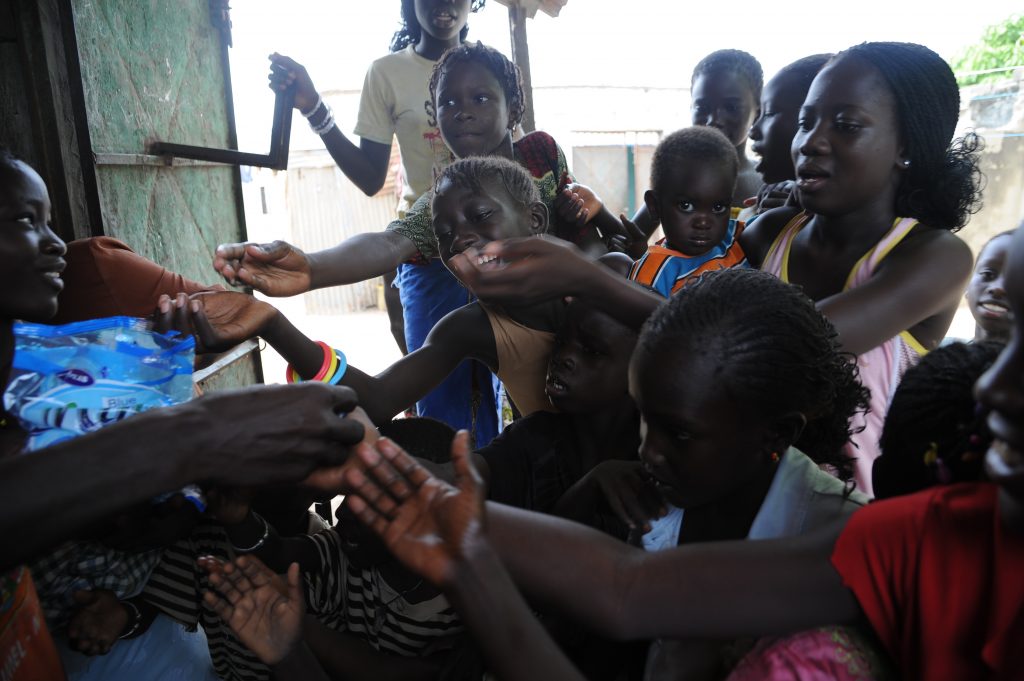 Villagers in M'Bour, Senegal reach for candy in the local shop. (Image © Meredith Mullins.)