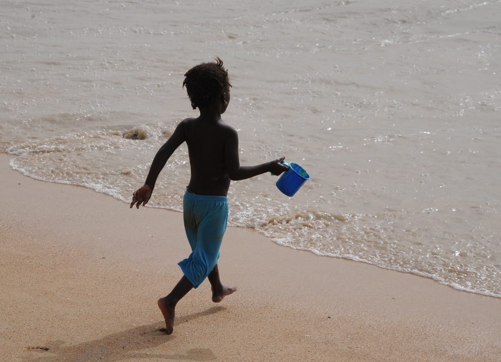 Boy runs to the ocean in M'Bour, Senegal, offering travel adventures and a photographer's dream of images. (Image © Meredith Mullins.)