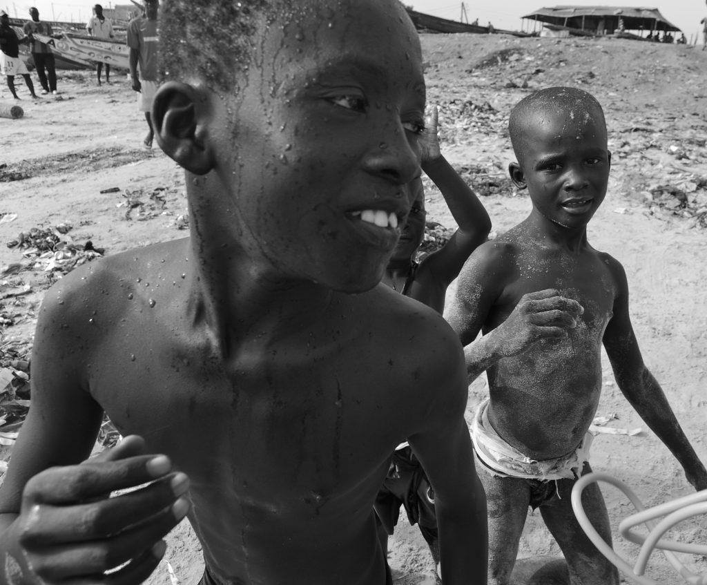Three boys on the beach in M'Bour, Senegal (B&W and close up), offering travel adventures and a photographer's dream in images. (Image © Meredith Mullins.)