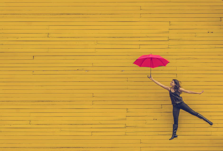 A woman flying with a pink umbrella, symbolizing women's efforts to advance women's rights to mobility and gender equality (image © Unsplash/Pexels).