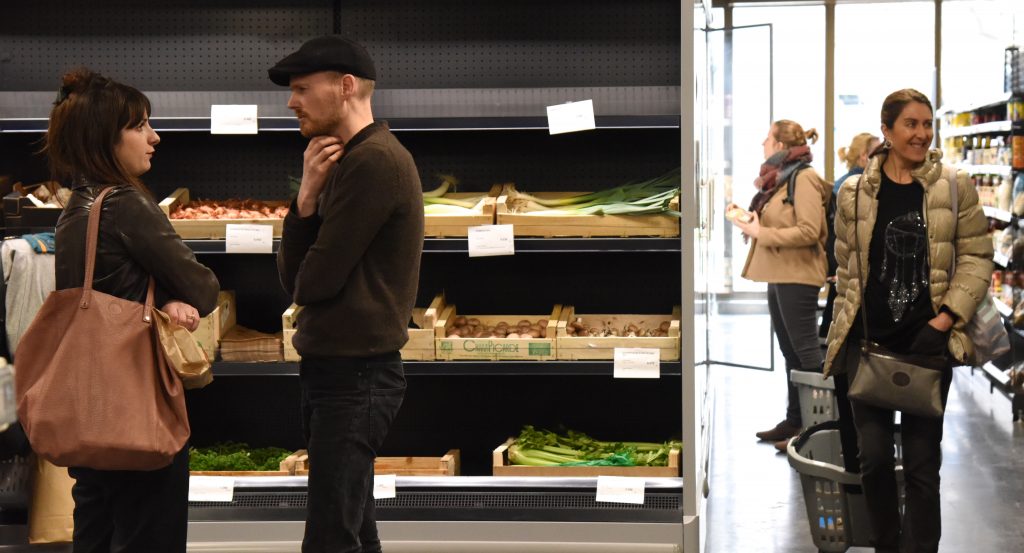 Two people chat at the food co-op La Louve in Paris, showing a successful blend of different cultures. (Image © Meredith Mullins.)