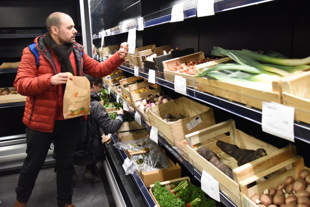 A man selects from the produce shelves at the Paris food co-op La Louve, an experiment in blending different cultures. (Image © Meredith Mullins.)