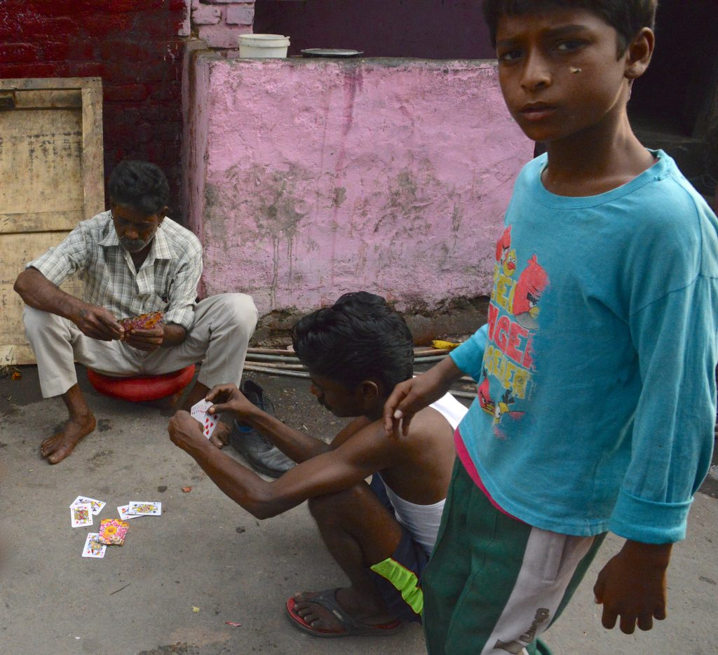 Men play cards in the street of the Kathputli Colony, showing cultural encounters in the slums of India. (Image © Meredith Mullins.)