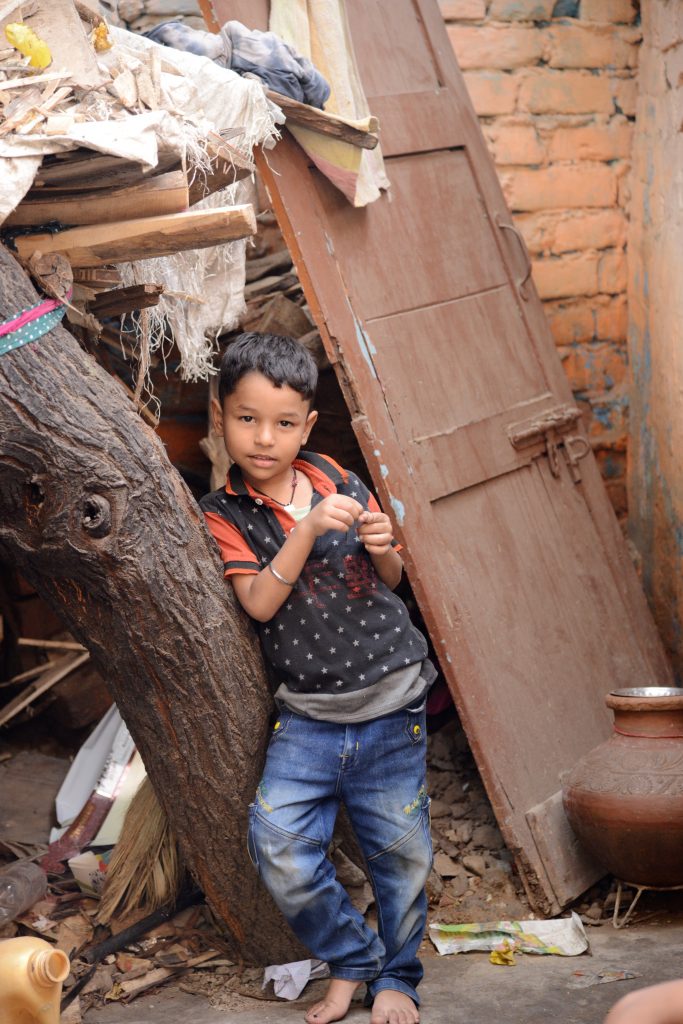 A boy poses amidst the rubble of the Kathputli Colony, showing cultural encounters in the slums of India. (Image © Meredith Mullins.)