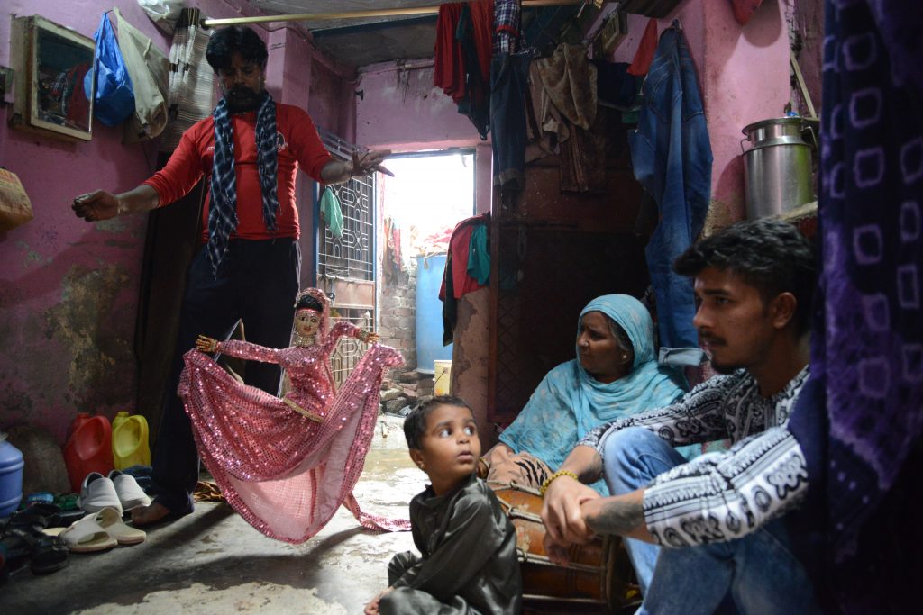 A puppeteer performs for his family in the Kathputli Colony in Delhi, showing cultural encounters in the slums of India. (Image © Meredith Mullins.)