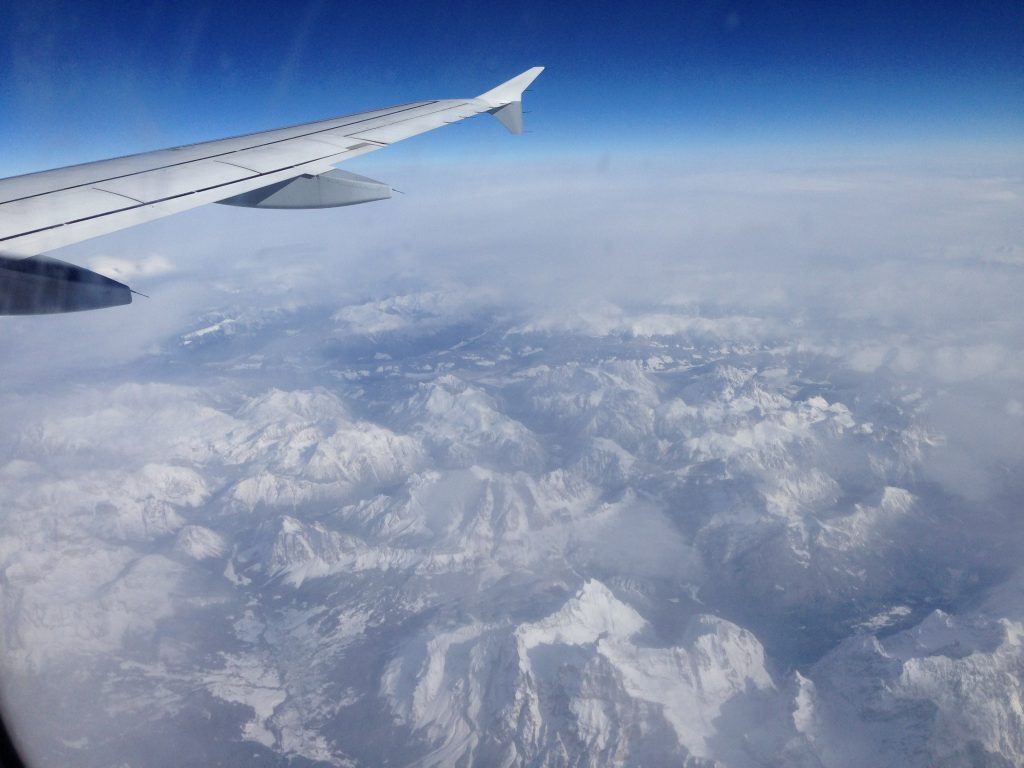 View of Alps from airplane window, offering travel adventures and air travel stories that inspire us. (Image © Meredith Mullins.)