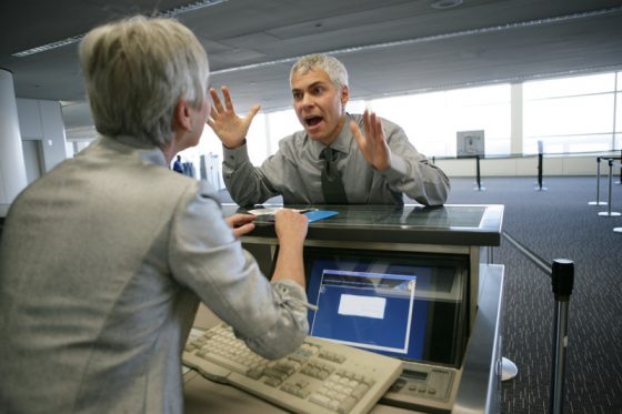 Man yelling at checkin, showing that travel adventures are not always pleasant and air travel stories do not always end well. (Image © Eyecandy Images.)