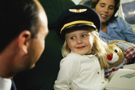 Girl by mother looking at pilot, showing how travel adventures and air travel stories begin. (Image © David De Lossy/Photodisc.)