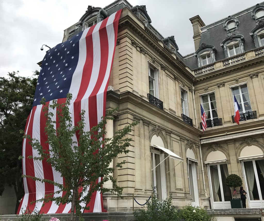 Large American flag and smaller French flags at the American Embassy Residence in Paris France, as we are crossing cultures in celebration of Independence Day. (Image © Meredith Mullins.)
