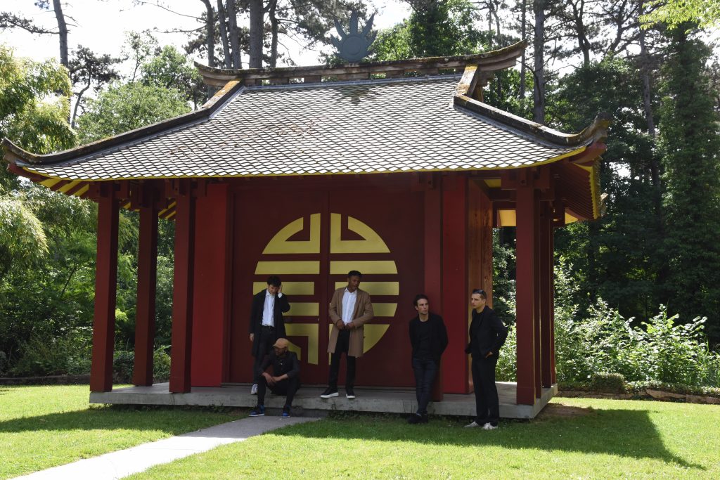 Chinese pavilion with young men in front in the Jardin d'agronomie Tropicale, one of the hidden gardens in Paris where visitors can be traveling the world. (Image © Meredith Mullins.)