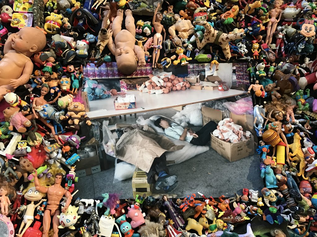 Sleeping Chinese worker at toy factory, part of Michael Wolf's installation The Real Toy Story, crossing cultures to show life in cities. (Image © Meredith Mullins/Installation and Photo © Michael Wolf.)