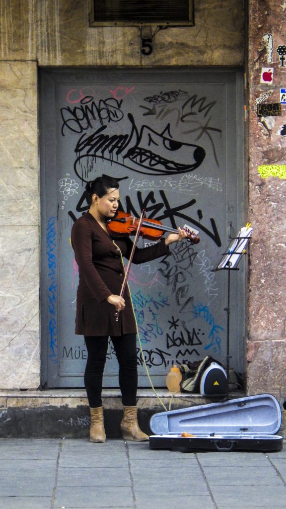 A woman playing violin on the street in Mexico City, showing that sound helps us see things differently (image © Eva Boynton).