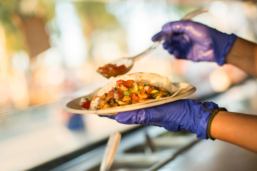 A vendor with a plate of tacos and a spoon of salsa, showing life in Mexico City (image©alexsalcedo/iStock). 