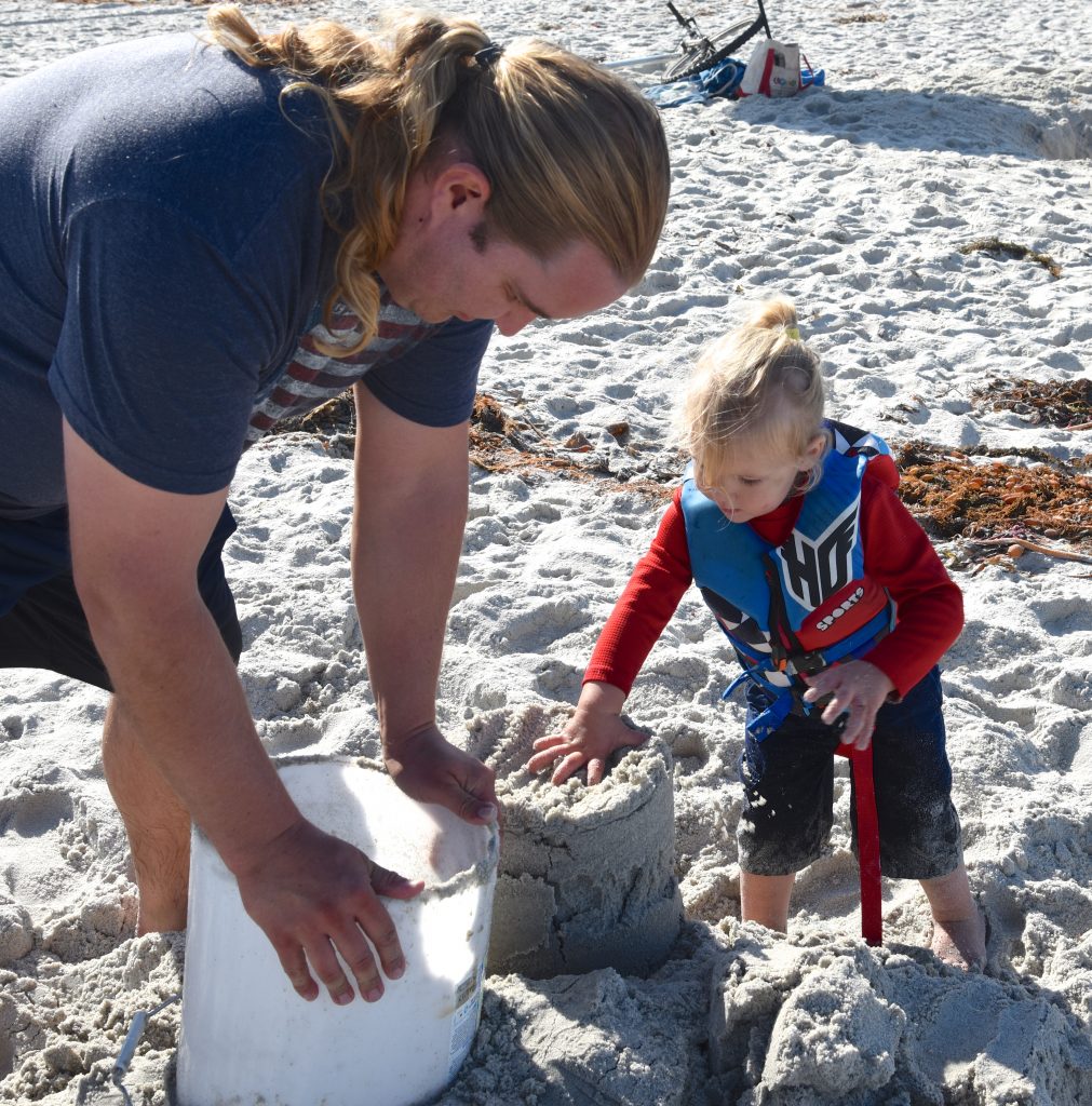 Dad and child make a sand sculpture at the Great Carmel Sand Castle Contest, discovering the art of sand sculptures. (Image © Meredith Mullins.)