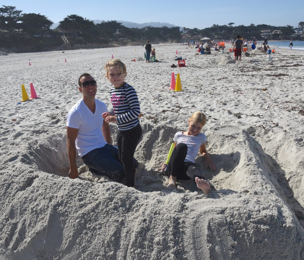 Family inside sand sculpture at the Great Carmel Sand Castle Contest, discovering the art of sand sculptures. (Image © Meredith Mullins.)