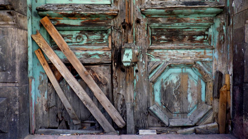 An old door with chipping wood and paint, showing life in Mexico City (image © Eva Boynton).