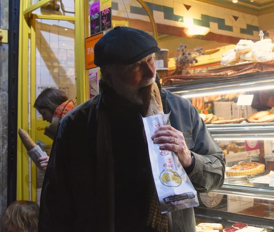 Man eating end of a baguette in Paris, France, illustrating rules of baguettiquette, a word invented via wordplay with the French language. (Image © Meredith Mullins.)