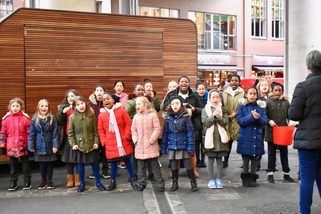 Children caroling at Borough Market, London inspire onlookers during an English holiday ramble. (Image © Joyce McGreevy)