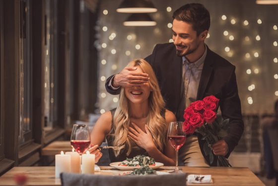 Couple on a date on Valentine's Day, showing cultural traditions of the holiday with roses and dinner. (Image © George Rudy/iStock.)
