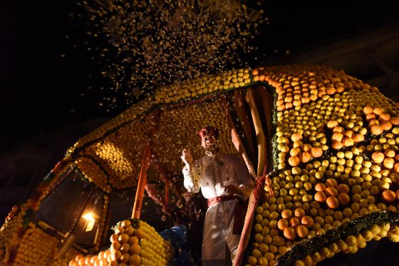 Parade float with Indian man throwing confetti at the Menton Lemon Festival, travel inspiration for unusual events. (Image © Meredith Mullins.)