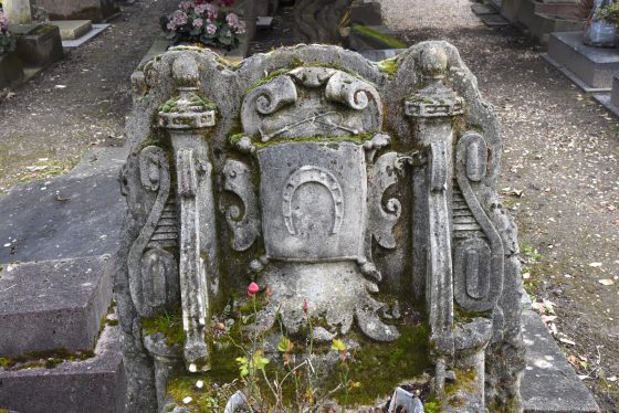 Tombstone with a horseshoe at the Paris pet cemetery, showing cultural traditions for saying farewell to pets. (Image © Meredith Mullins.)