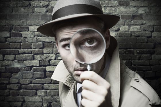 Detective with magnifying glass, part of the new trend of escape rooms around the world which enable cultural encounters and teach life lessons. (Image © demaerre/iStock.)