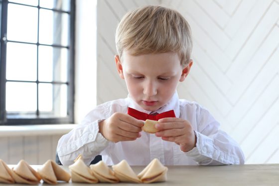 Cute boy with row of fortune cookies, looking for the right fortune from all the proverbs and sayings. (Image © Yeko Photo Studio/iTunes.)