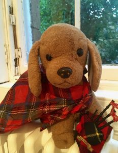 A toy canine travel mascot named Bedford, dressed in Scottish tartan, inspires his human travel buddy to see the world differently. (Image © Joyce McGreevy)