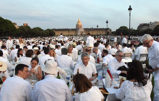Dîner en Blanc at the Esplanade des Invalides in Paris, where guests enjoy the cultural traditions of the Dinner in White. (Image © Meredith Mullins.)