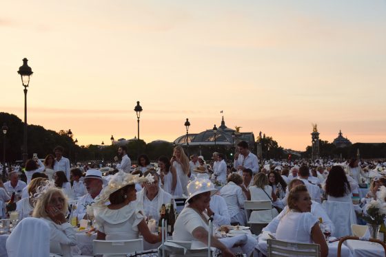 Dîner en Blanc guests in front of the Grand Palais in Paris, enjoying the cultural traditions of the Dinner in White. (Image © Meredith Mullins.)