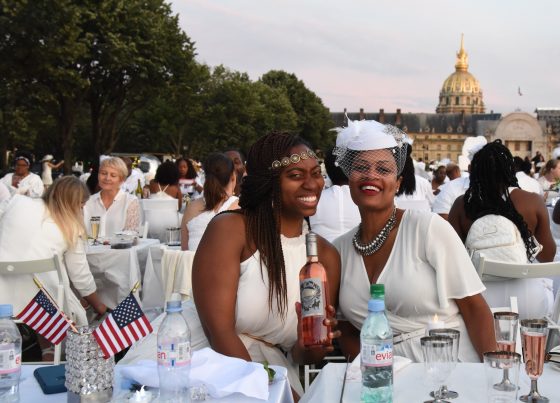 Two women from the U.S. are celebrating at the Paris Dîner en Blanc, enjoying the cultural traditions of the Dinner in White. (Image © Meredith Mullins.)