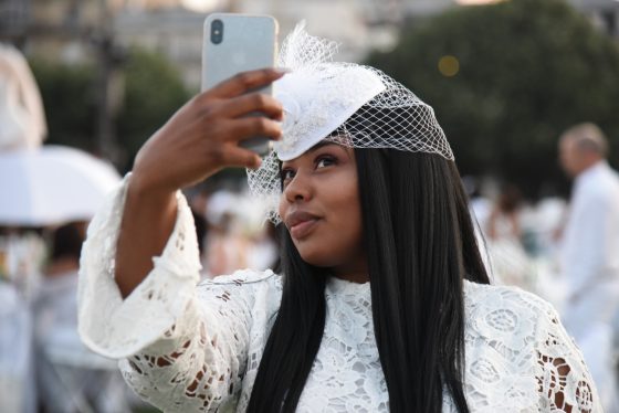 Woman taking selfie at the Paris Dîner en Blanc, enjoying the cultural traditions of the Dinner in White. (Image © Meredith Mullins.)