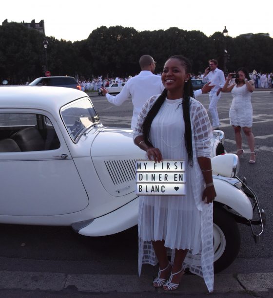 Woman with first-time sign at the Paris Dîner en Blanc, enjoying the cultural traditions of the Dinner in White. (Image © Meredith Mullins.)