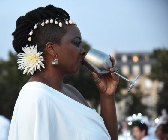 Woman with silver wine goblet at the Paris Dîner en Blanc, enjoying cultural traditions of the Dinner in White. (Image © Meredith Mullins.)