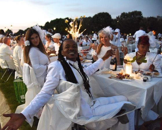 Four happy Dîner en Blanc guests at the table, enjoying the cultural traditions of the Dinner in White in Paris. (Image © Meredith Mullins.)
