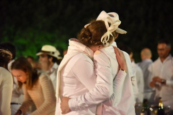 A couple embracing at the Paris Dîner en Blanc, enjoying cultural traditions of the Dinner in White. (Image © Meredith Mullins.)