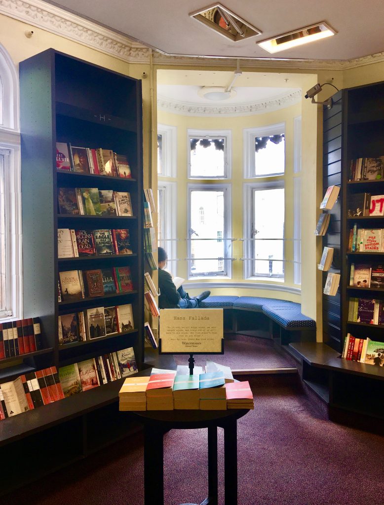 A woman reading in a window seat of a bookshop in Bloomsbury, London symbolizes the pleasures of reading while traveling, a wanderlust for words. (Image © Joyce McGreevy)