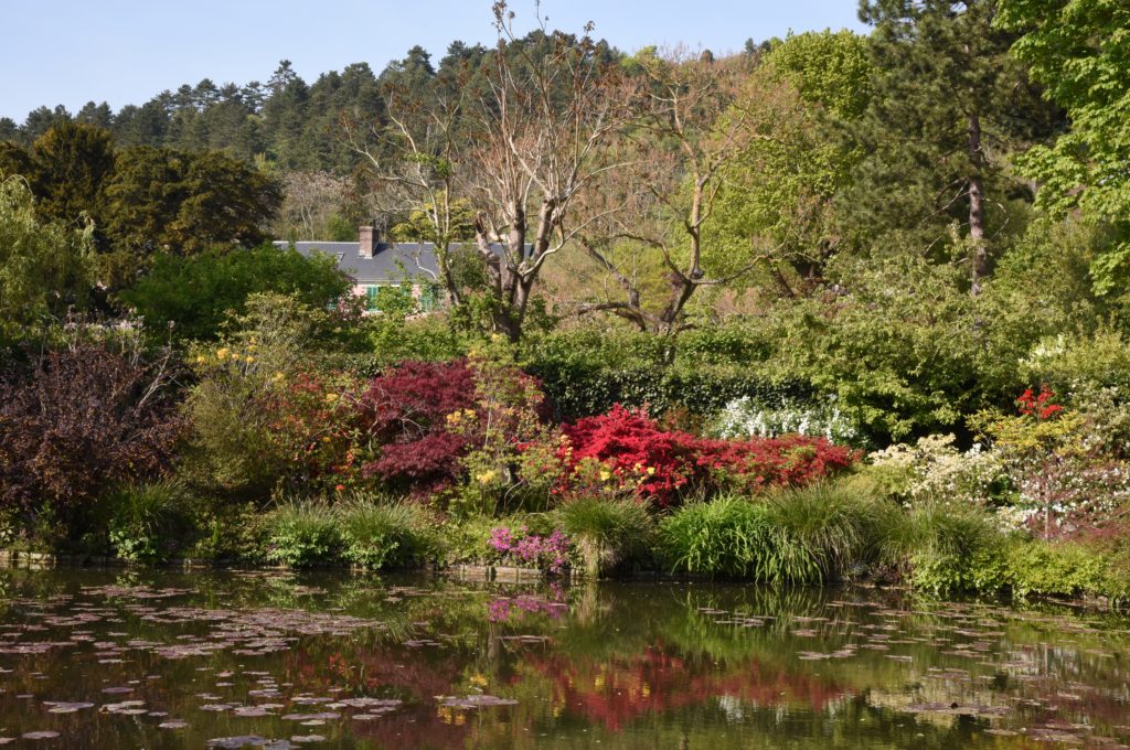 Monet's Giverny gardens with azaleas and house in the distance, travel inspiration for Monet fans and artists. (Image © Meredith Mullins.)