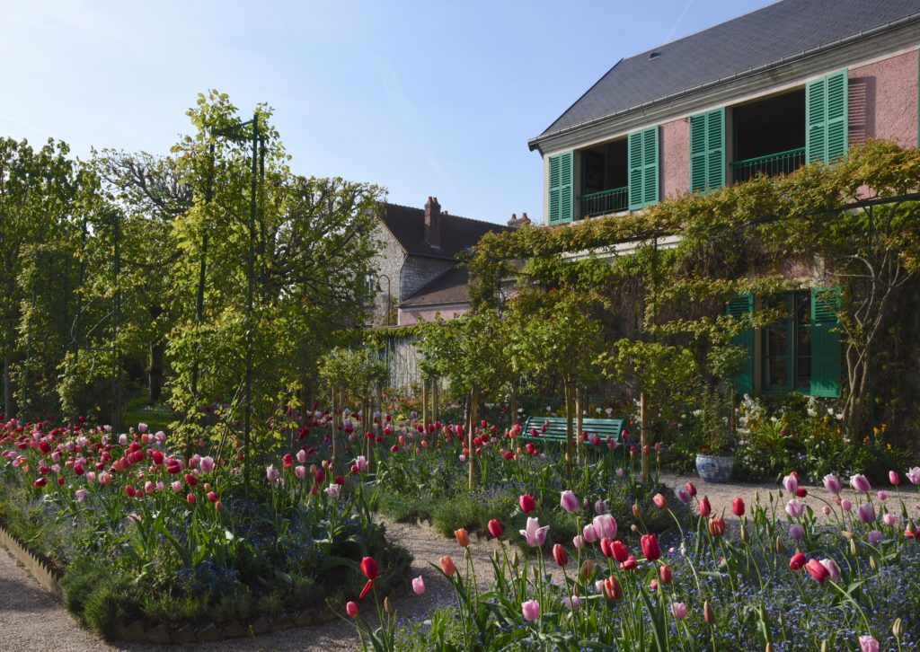Monet's house at Giverny gardens with spring tulips, travel inspiration for visitors and artists following Monet's path. (Image © Meredith Mullins.)