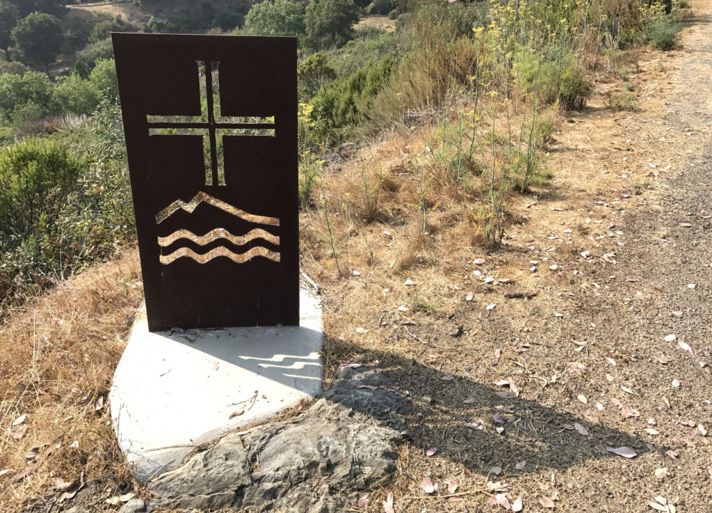 Iron sign for the New Camaldoli Hermitage in Big Sur, a place for seeking silence and challenging the cultural traditions of Labor Day. (Image © Meredith Mullins.)