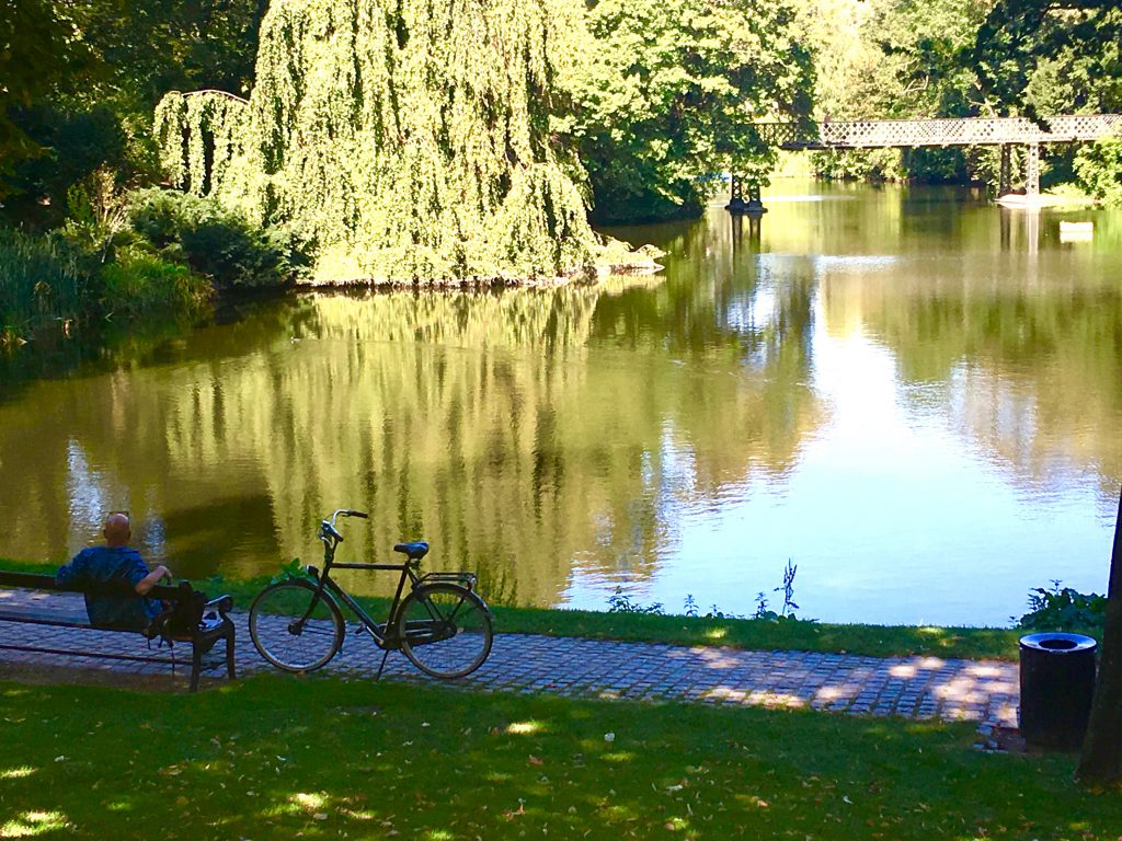 A bicyclist in a park in Copenhagen, Denmark appreciates the discoveries inherent in urban peace and quiet. (© Joyce McGreevy)