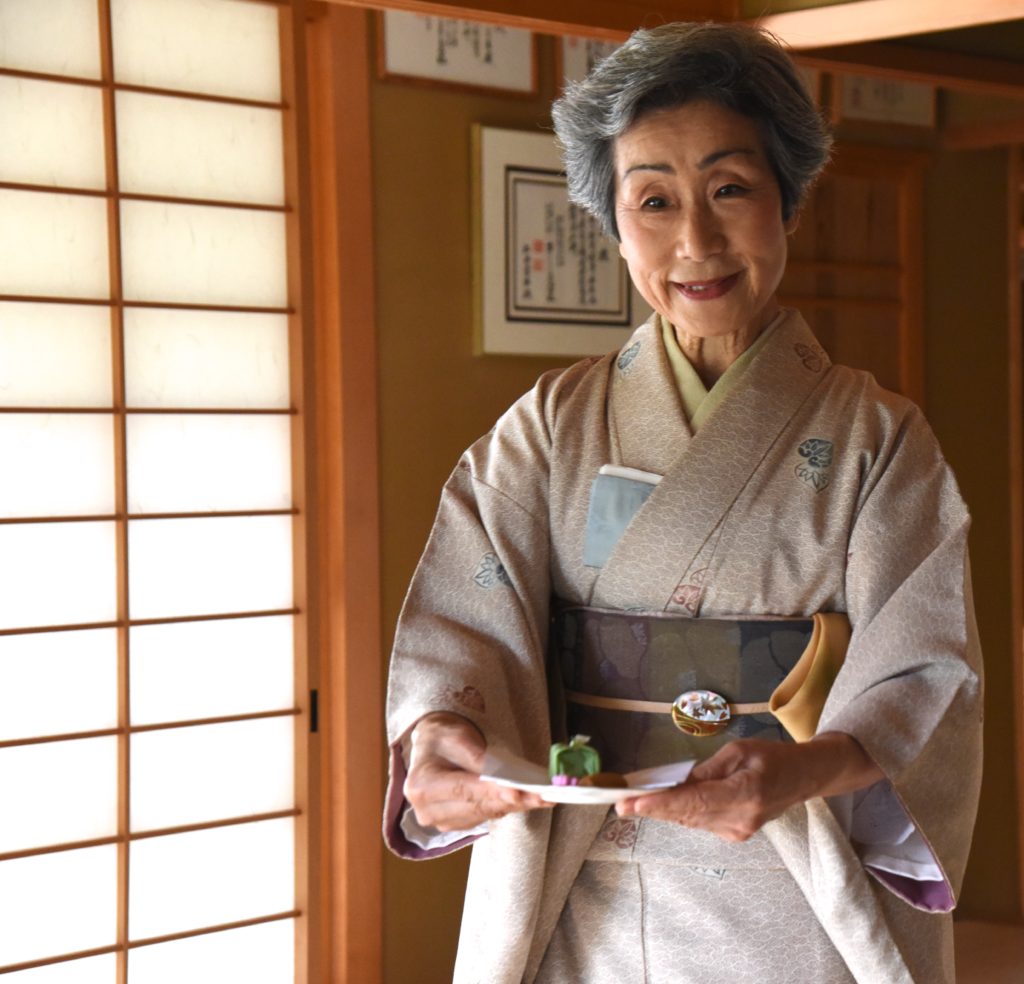 Japanese woman offers sweets in a Japanese tea ceremony, showing the cultural traditions of Japan. (Image © Meredith Mullins.)