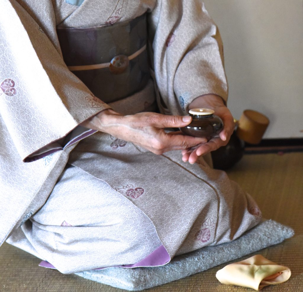 Japanese woman presents a tea caddy for the Japanese tea ceremony, showing the cultural traditions of Japan. (Image © Meredith Mullins.)
