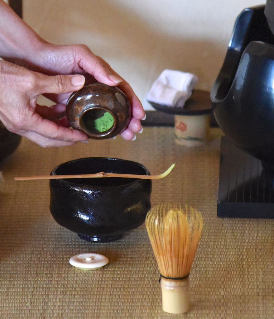 Close up of the tools of the Japanese tea ceremony as the host pours the matcha powder, showing the cultural traditions of Japan. (Image © Meredith Mullins.)