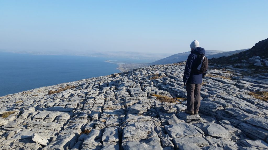A hiker contemplates the limestone pavement and Atlantic Ocean view from the Burren, a geological wonder in Ireland, one of the most amazing places on Earth. (Image © Ciana Campbell)