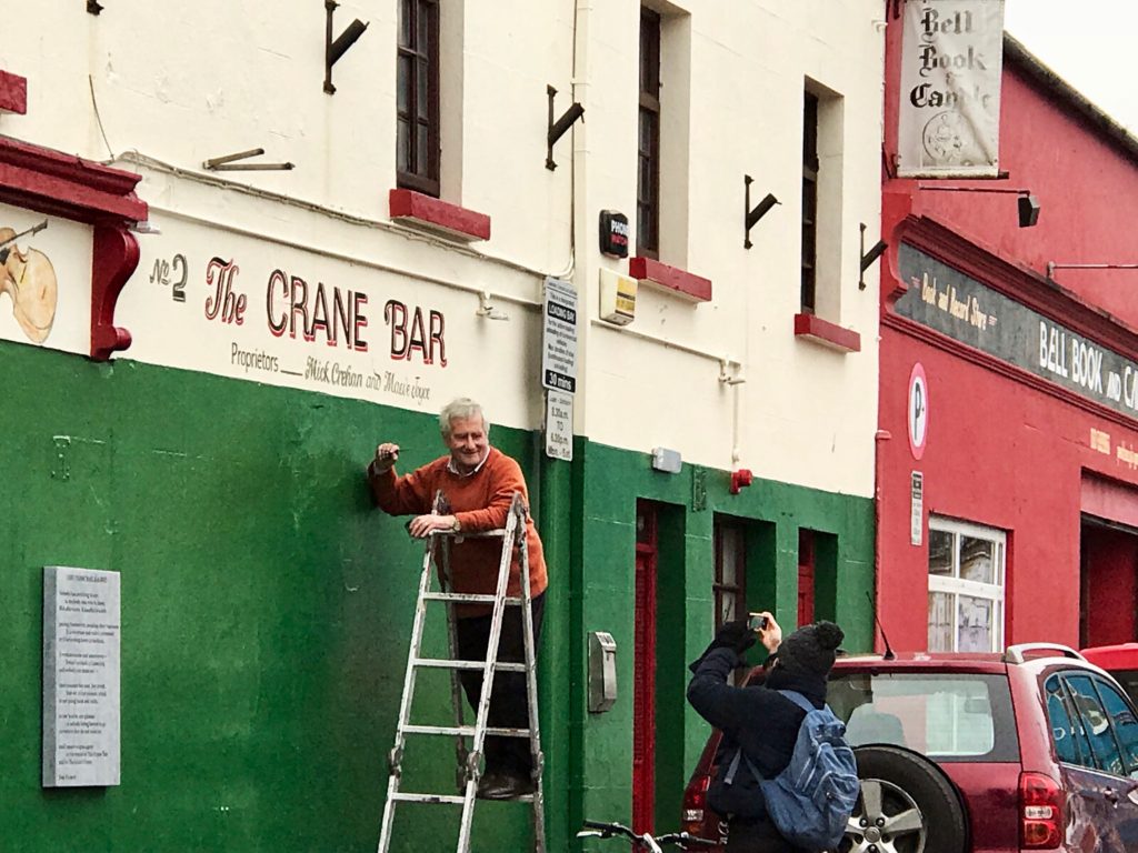 A sign painter and photographer at the Crane Bar,  Galway reflect the friendliness that inspires wanderlust for Ireland. (Image © Carolyn McGreevy)