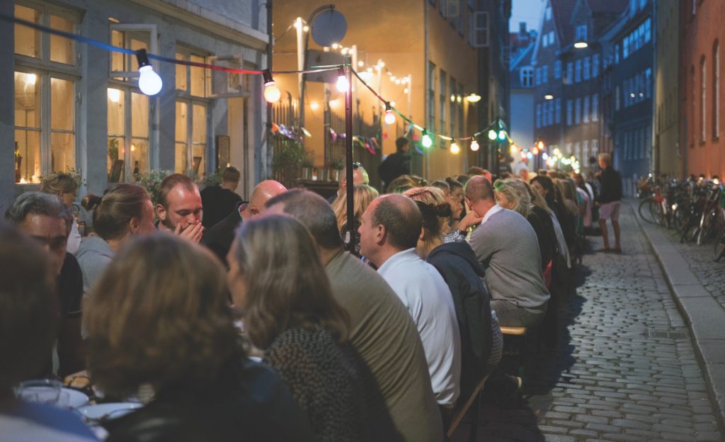 Diners celebrate community at one long outdoor table in Aarhus, designed to inspire aha moments by rethinking food and fellowship. (Image © Stefan Ravn/Aarhus 2017)